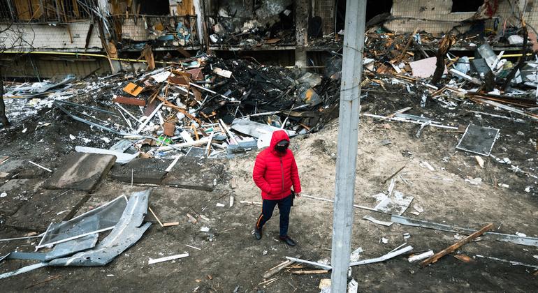 Un hombre camina frente al crater dejado por la explosicón de una bomba en Kyiv, capital de Ucrania.